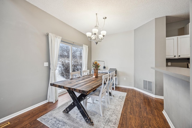 dining space featuring dark wood-type flooring, a chandelier, and a textured ceiling