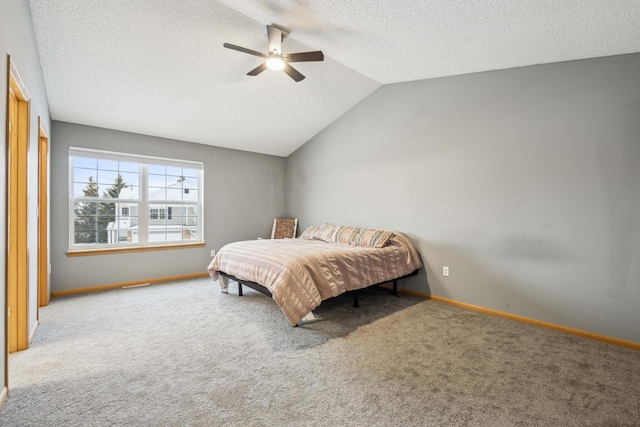 bedroom featuring ceiling fan, carpet flooring, vaulted ceiling, and a textured ceiling