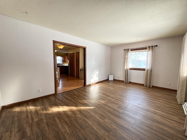 unfurnished room featuring wood finished floors, baseboards, and a textured ceiling