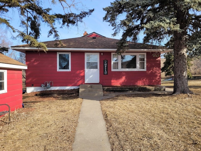 bungalow-style house featuring entry steps, a front lawn, and roof with shingles