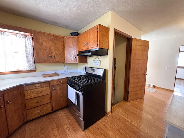 kitchen with under cabinet range hood, a wealth of natural light, brown cabinets, and stainless steel range with gas stovetop