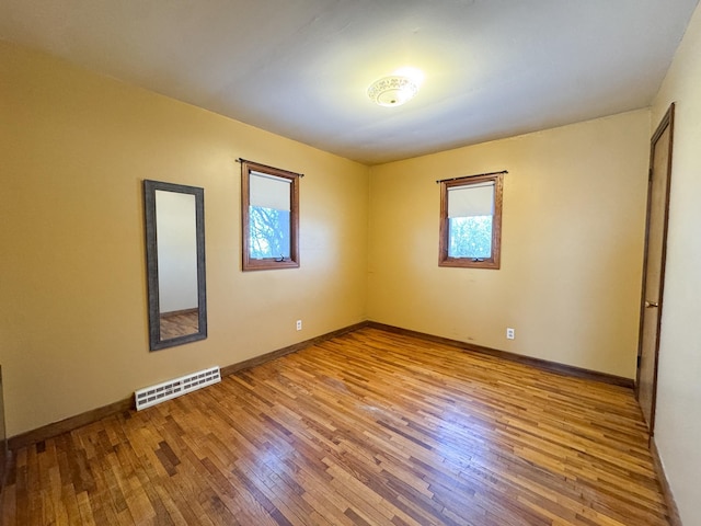 spare room featuring hardwood / wood-style flooring, a healthy amount of sunlight, and visible vents