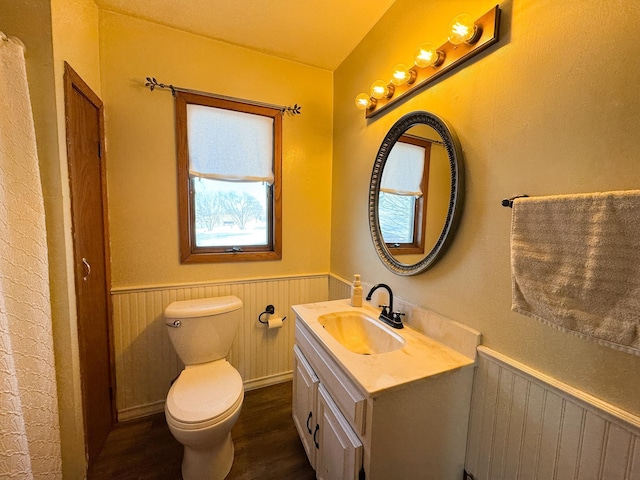 bathroom featuring a wainscoted wall, toilet, vanity, and wood finished floors