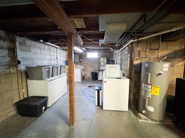 basement featuring washing machine and clothes dryer, electric panel, and electric water heater