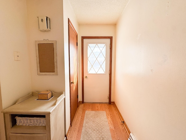 doorway to outside featuring a textured ceiling and light wood finished floors