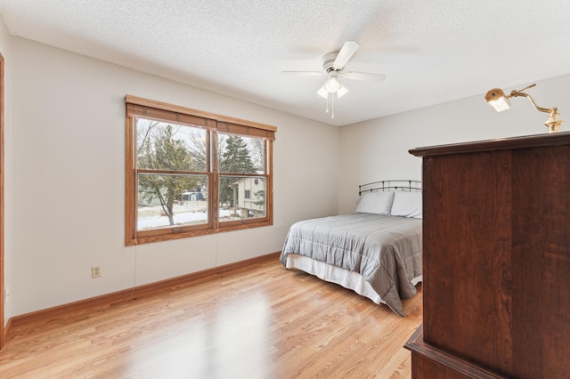 bedroom with ceiling fan, a textured ceiling, and light wood-type flooring