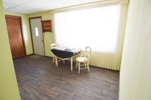 dining space with dark hardwood / wood-style flooring and a drop ceiling