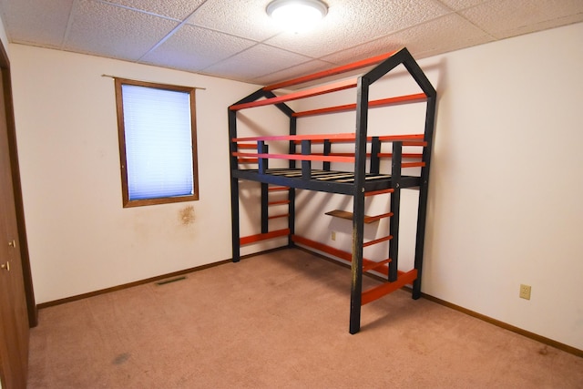 bedroom featuring light carpet and a drop ceiling