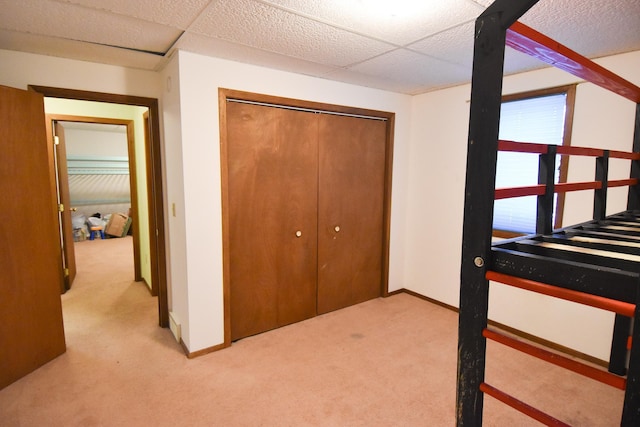 carpeted bedroom with a paneled ceiling and a closet