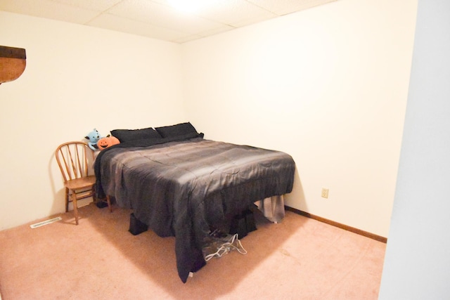 bedroom featuring light carpet and a drop ceiling