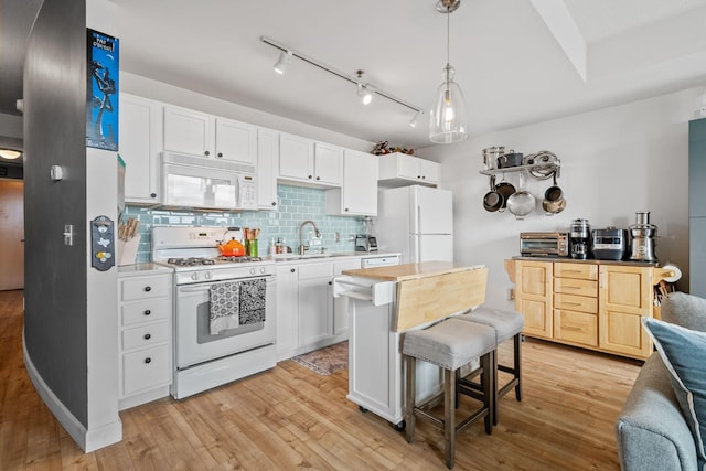 kitchen with tasteful backsplash, light wood-type flooring, pendant lighting, white appliances, and white cabinets