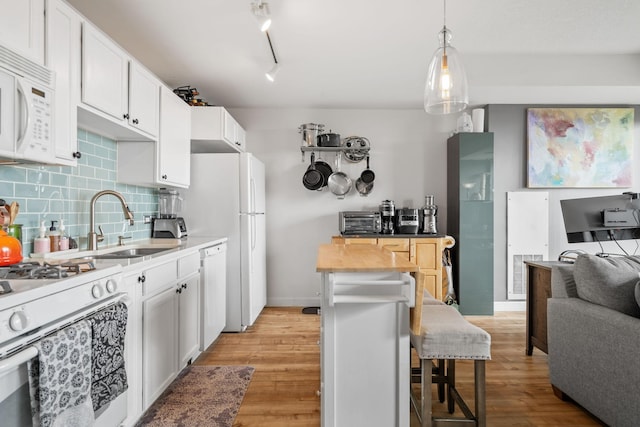 kitchen with white cabinetry, a breakfast bar area, white appliances, and decorative backsplash