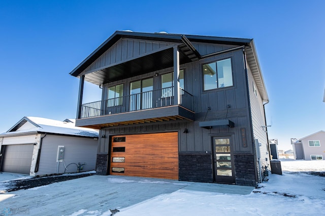 view of front of home with board and batten siding, stone siding, a balcony, and central air condition unit