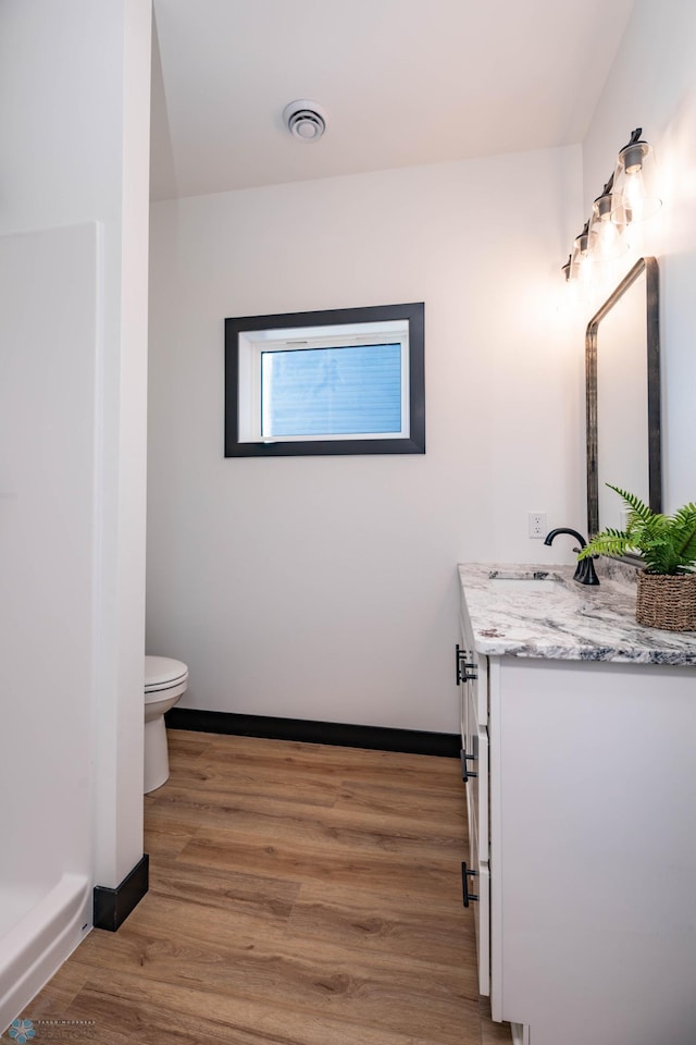 bathroom featuring toilet, wood finished floors, vanity, visible vents, and baseboards