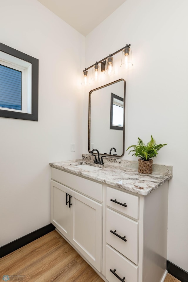 bathroom featuring baseboards, wood finished floors, and vanity