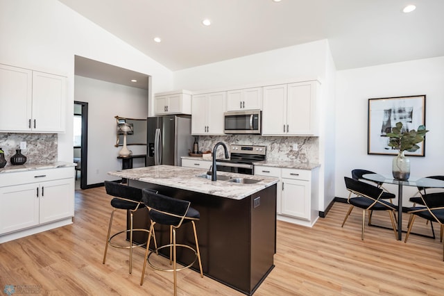 kitchen featuring white cabinets, stainless steel appliances, a sink, and an island with sink