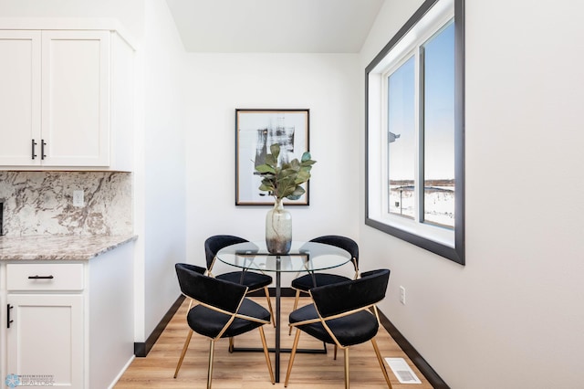 dining room with light wood-type flooring, visible vents, and baseboards