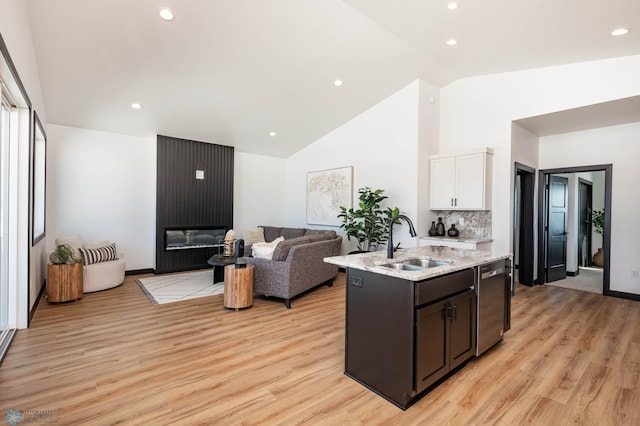 kitchen featuring a sink, white cabinets, open floor plan, light wood-type flooring, and dishwasher