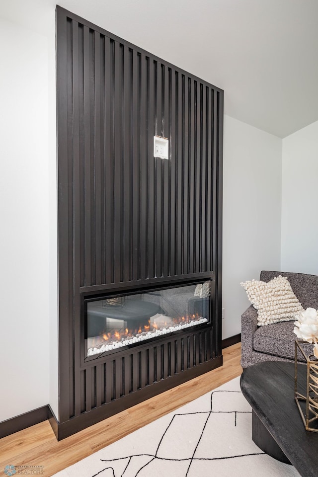 details with a lit fireplace, baseboards, and wood finished floors