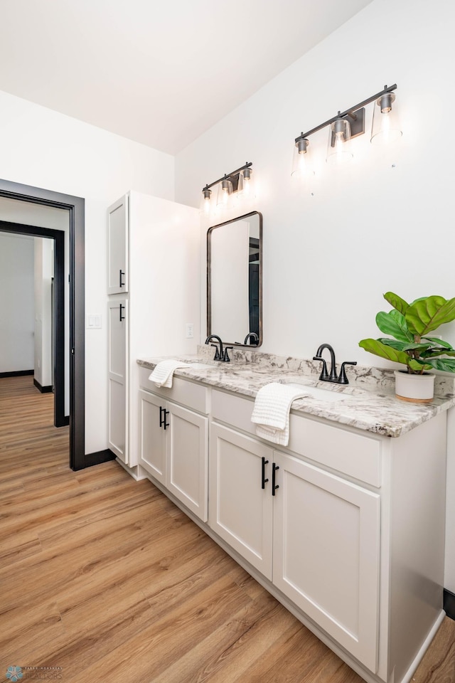 bathroom featuring double vanity, a sink, and wood finished floors