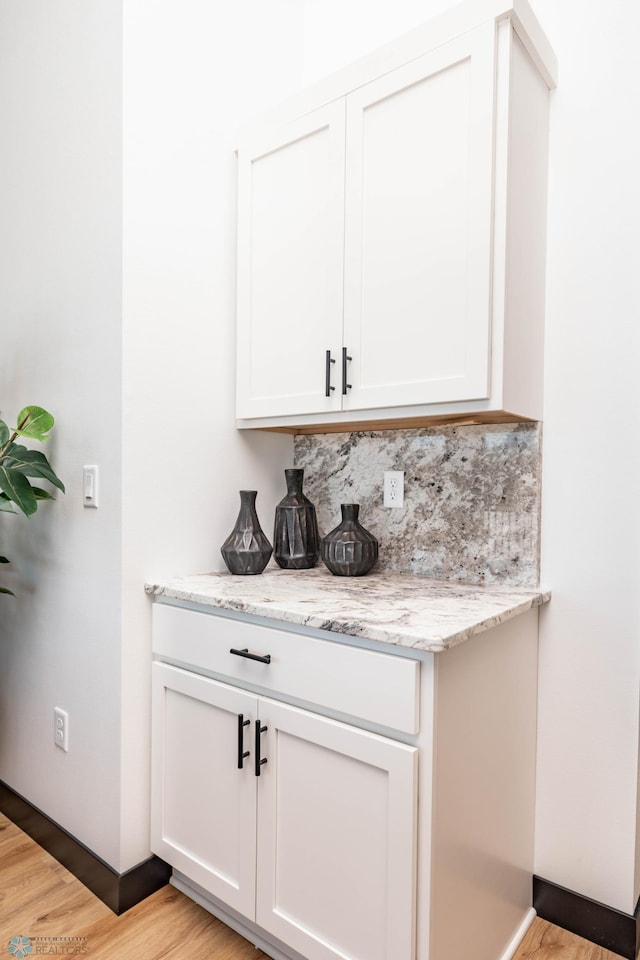 bar featuring light wood-type flooring and backsplash