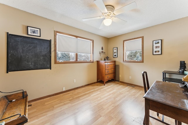 home office featuring a textured ceiling, ceiling fan, and light hardwood / wood-style flooring