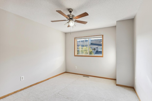 empty room featuring carpet flooring, visible vents, a textured ceiling, and baseboards