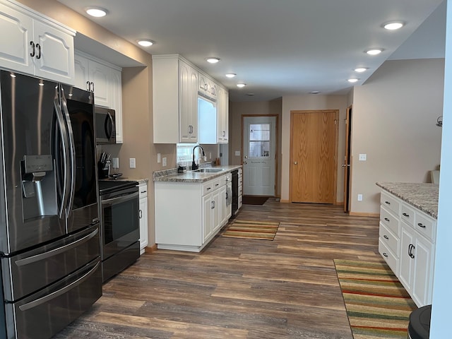 kitchen featuring appliances with stainless steel finishes, sink, white cabinets, dark hardwood / wood-style flooring, and light stone countertops