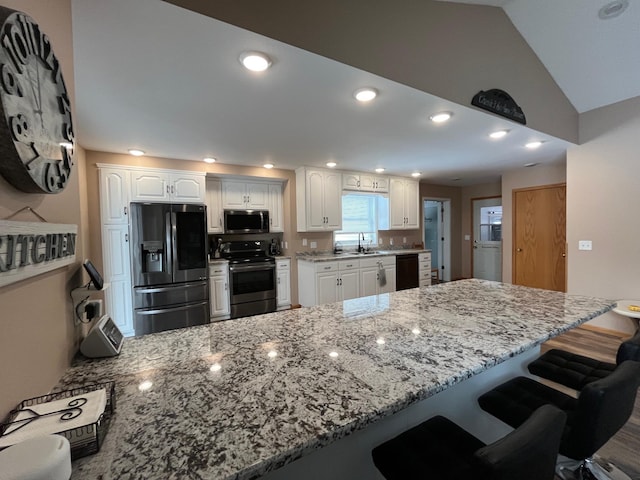 kitchen with appliances with stainless steel finishes, sink, white cabinets, and kitchen peninsula