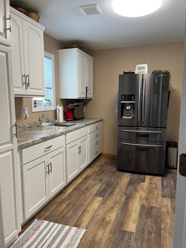 kitchen featuring dark wood-type flooring, stainless steel fridge, sink, and white cabinets