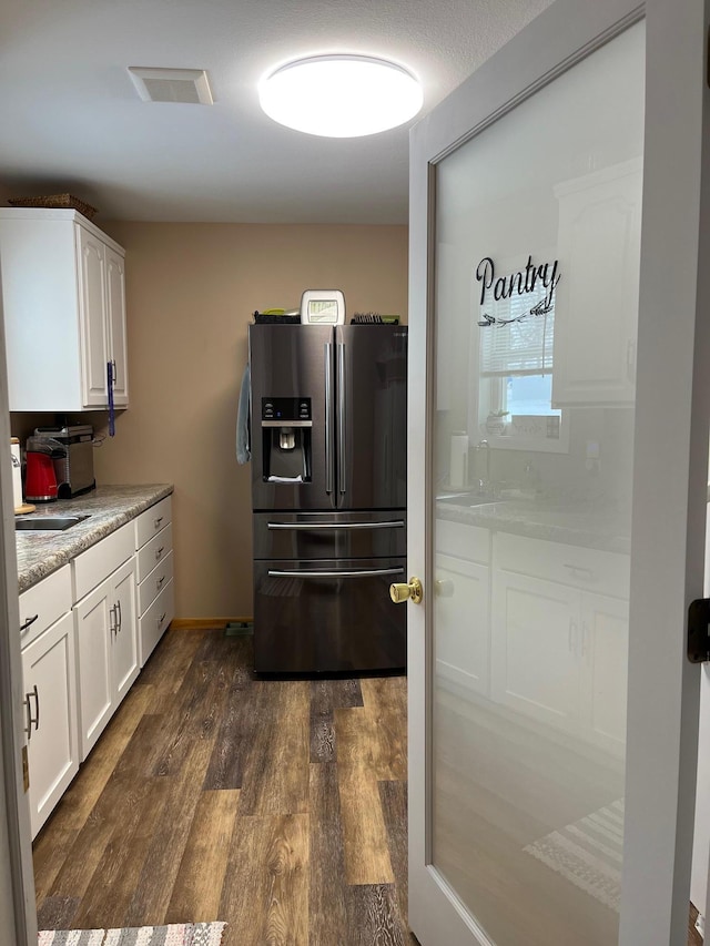 kitchen featuring stainless steel fridge, dark hardwood / wood-style flooring, sink, and white cabinets