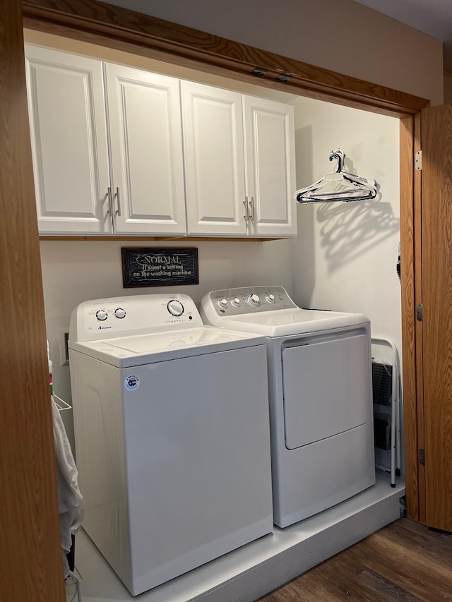 laundry area with cabinets, washing machine and clothes dryer, and dark wood-type flooring