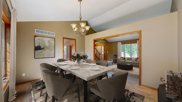 dining room with hardwood / wood-style flooring, lofted ceiling, and a chandelier