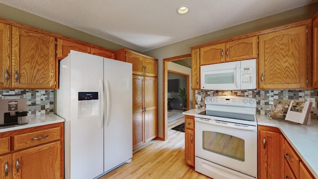 kitchen with backsplash, white appliances, a textured ceiling, and light wood-type flooring