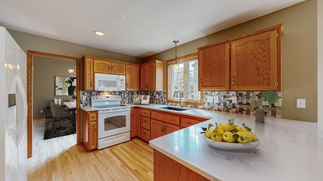 kitchen featuring sink, white appliances, tasteful backsplash, decorative light fixtures, and kitchen peninsula