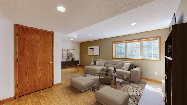 living room with a textured ceiling and light hardwood / wood-style flooring