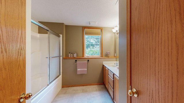 bathroom featuring vanity, a textured ceiling, and bath / shower combo with glass door