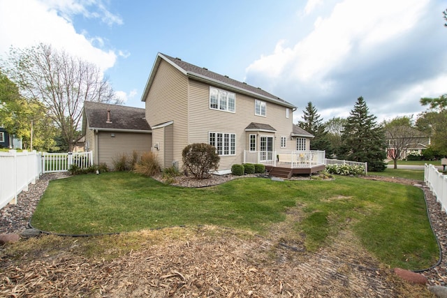 rear view of property featuring a wooden deck and a lawn