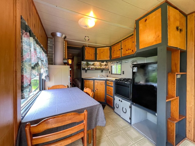 kitchen with decorative light fixtures, sink, a wood stove, and a wealth of natural light