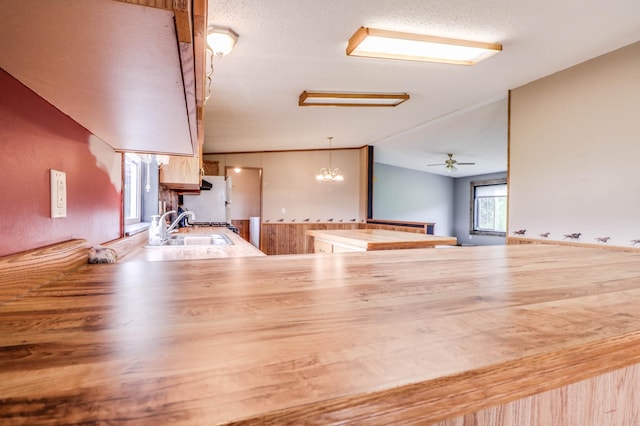 unfurnished living room featuring ceiling fan with notable chandelier, lofted ceiling, and sink