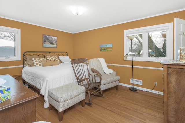 bedroom featuring ornamental molding and light hardwood / wood-style flooring