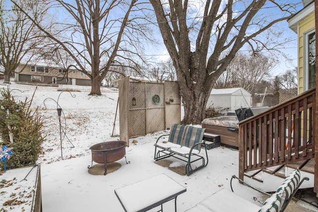 snow covered patio featuring a hot tub and an outdoor fire pit