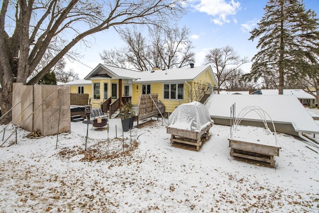 snow covered rear of property featuring a fire pit