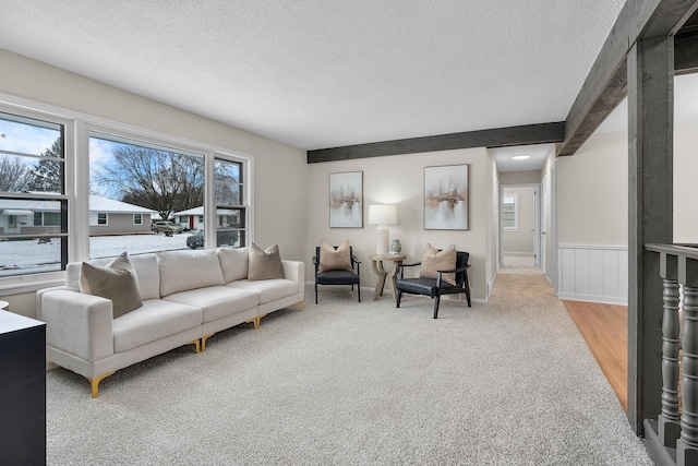 living room with light colored carpet, beam ceiling, and a textured ceiling