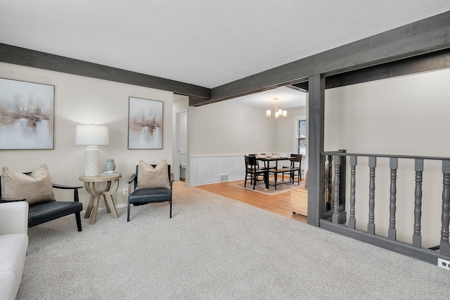 living area with beamed ceiling, carpet flooring, a chandelier, and a textured ceiling