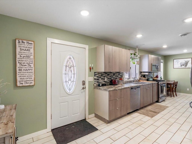 kitchen with appliances with stainless steel finishes, sink, and backsplash