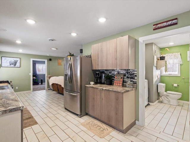 kitchen with stainless steel fridge with ice dispenser, backsplash, washer / dryer, and light tile patterned floors