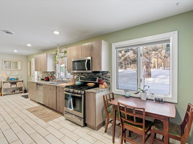 kitchen with tasteful backsplash, appliances with stainless steel finishes, sink, and light brown cabinetry