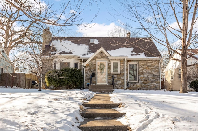 view of front of property with stone siding, a chimney, and fence