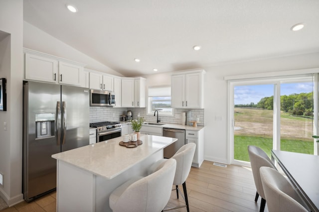 kitchen featuring white cabinetry, sink, decorative backsplash, a center island, and stainless steel appliances